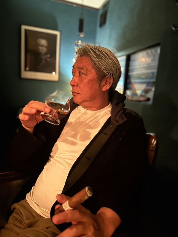夜のラウンジで葉巻を楽しむ西田理一郎