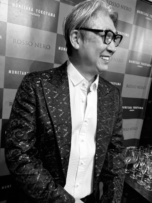 イベントのバックパネルの前に立つ西田理一郎（モノクロ）