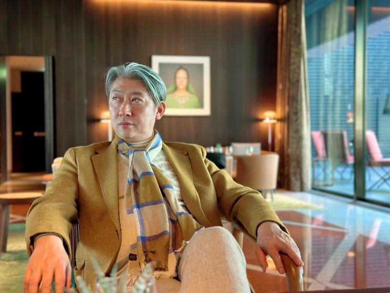 ホテルのラウンジでくつろぐキャメルコート姿の西田理一郎