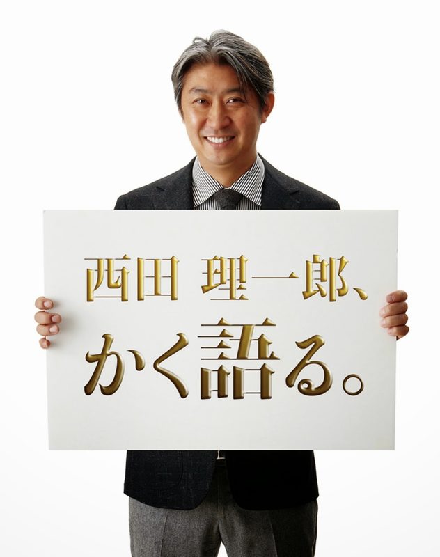 「西田理一郎、かく語る。」のボードを掲げる西田理一郎