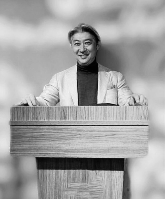 演台に立つ西田理一郎（モノクロ）