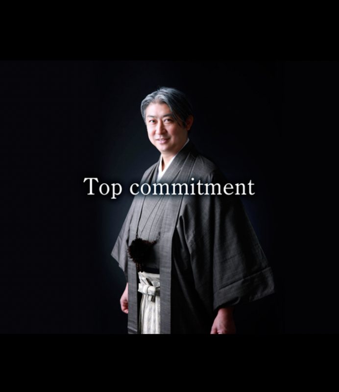 着物姿の西田理一郎と「Top commitment」の文字