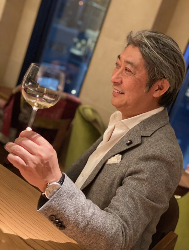 白ワインのグラスを掲げる西田理一郎
