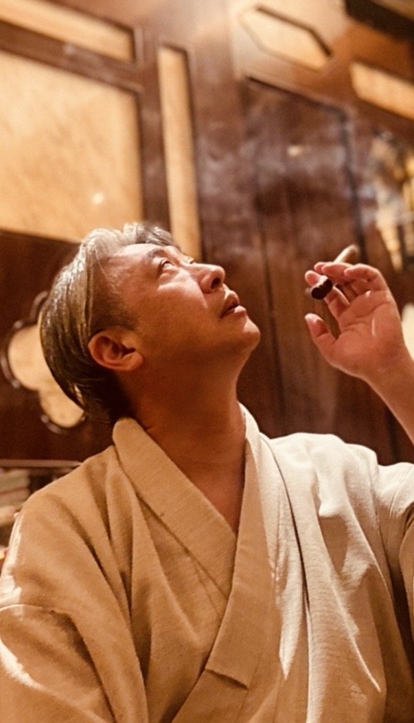着物姿で葉巻を手に天井を見上げる西田理一郎